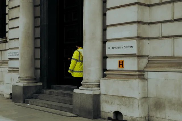 A guard in yellow jacket at the entrance of HM Revenue & Customs building in the UK. Five official property data sources, from Price Paid Data to the Companies House register