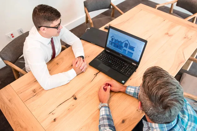 Professionals discuss architectural design on a laptop in a modern office setting. Property creators software selection: a pass or fail gate per risk