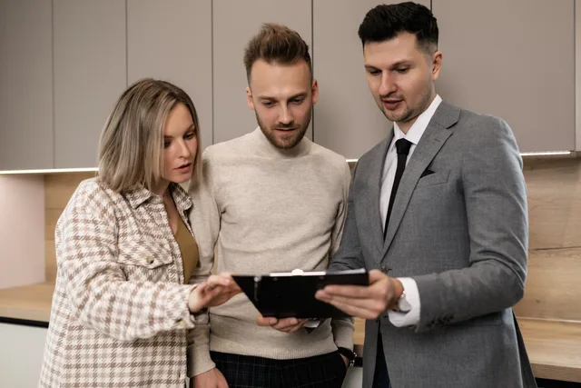 Real estate agent discussing property details with clients indoors. Eight roles in property media, each with authority over facts, rights or release